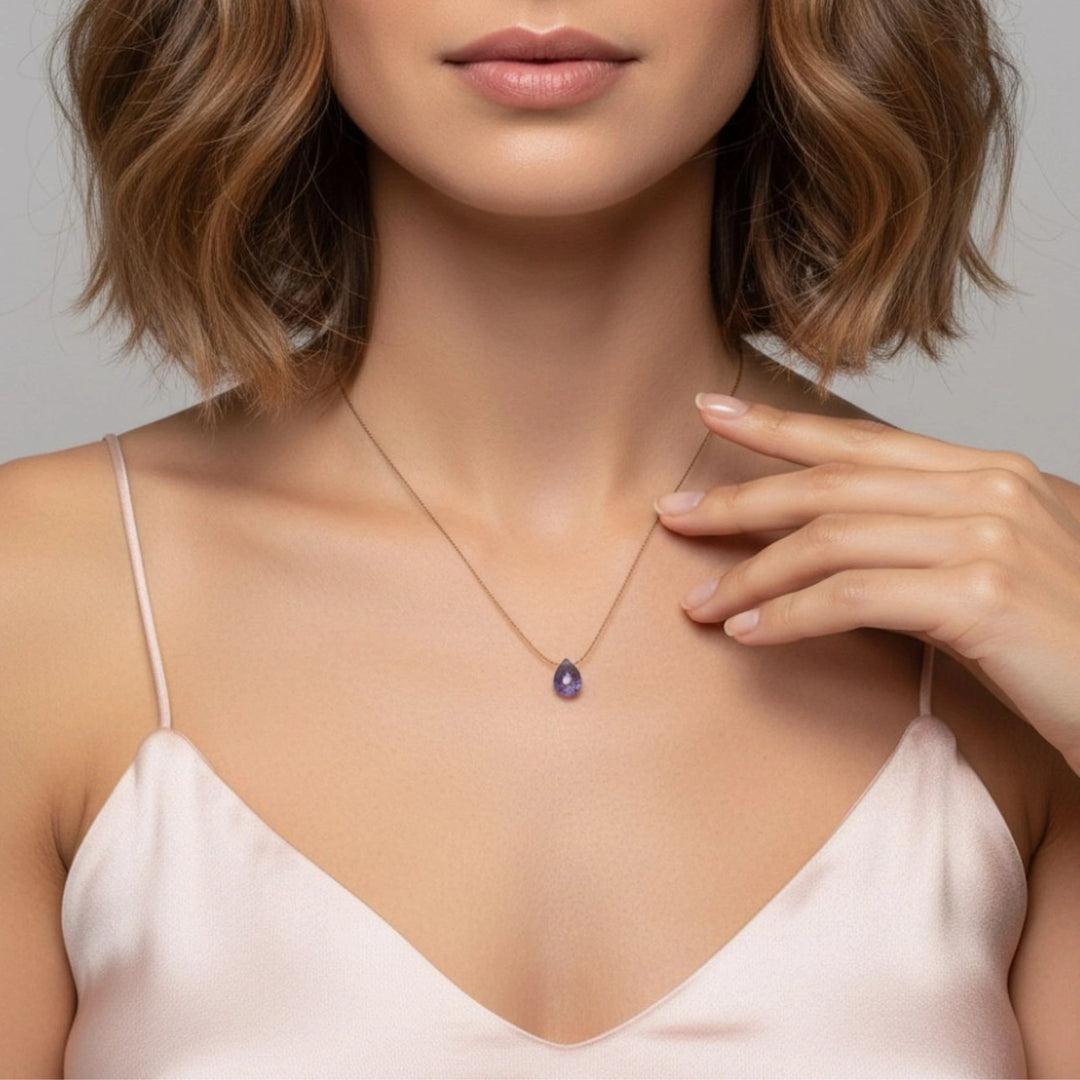 Woman wearing a necklace with a tanzanite pendant against a neutral background