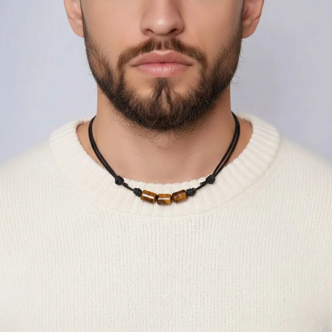 Man wearing a tigers eye necklace with a plain background