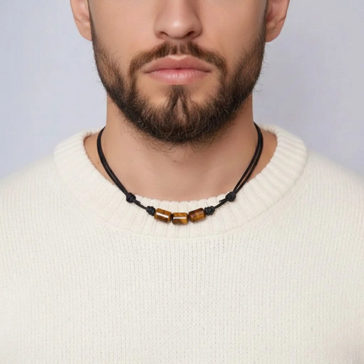 Man wearing a tigers eye necklace with a plain background