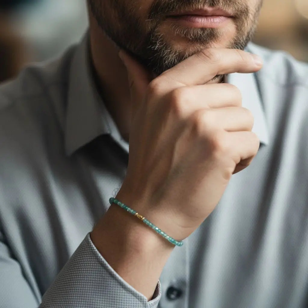 Man wearing a indicolite paraiba beaded bracelet on his wrist, with a blurred background.