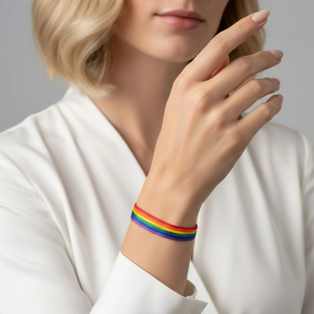 Person wearing a rainbow bracelet on a plain background