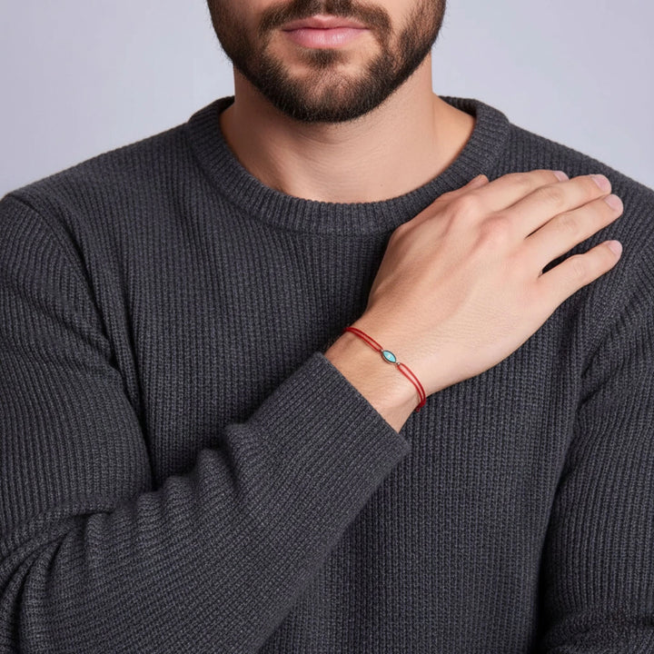 Man wearing a dark gray sweater with a red bracelet on his wrist.