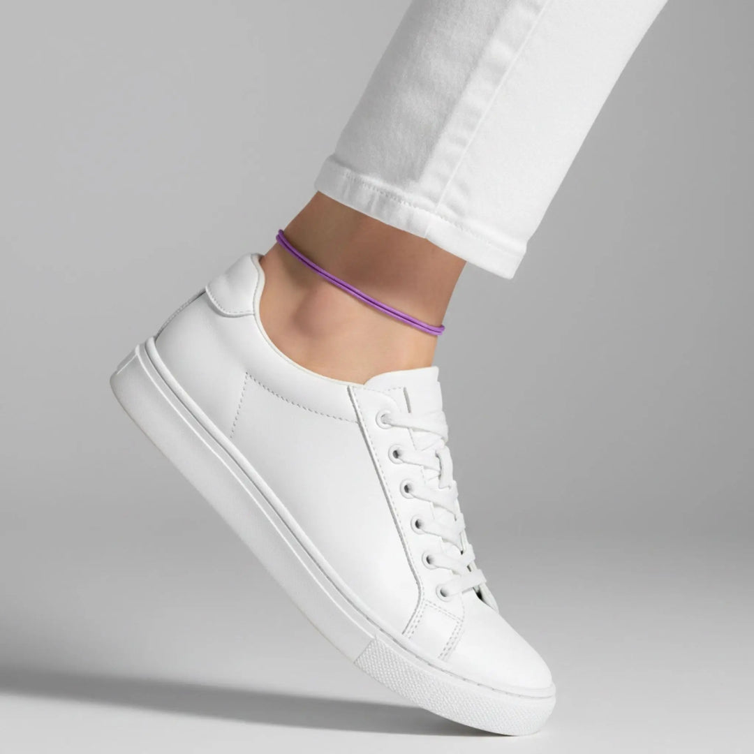 Purple anklet styled with a white sneaker against a gray background.