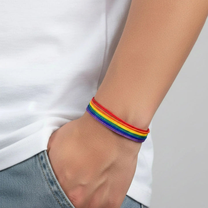 Person wearing a rainbow bracelet on a plain background