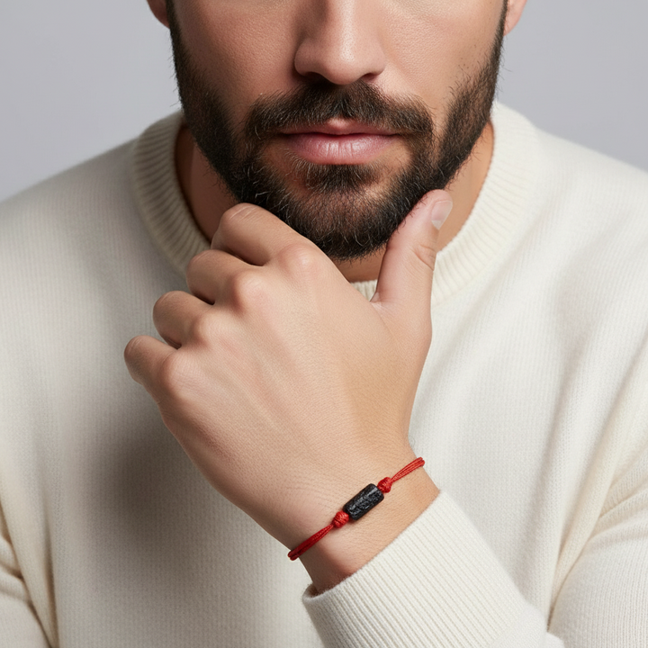 Man wearing chunky raw black tourmaline bracelet on red waxed nylon cord.
