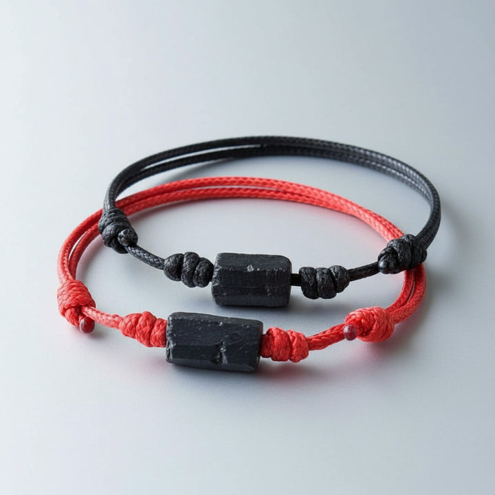 Two raw black tourmaline bead bracelets on red and black waxed nylon cords.

