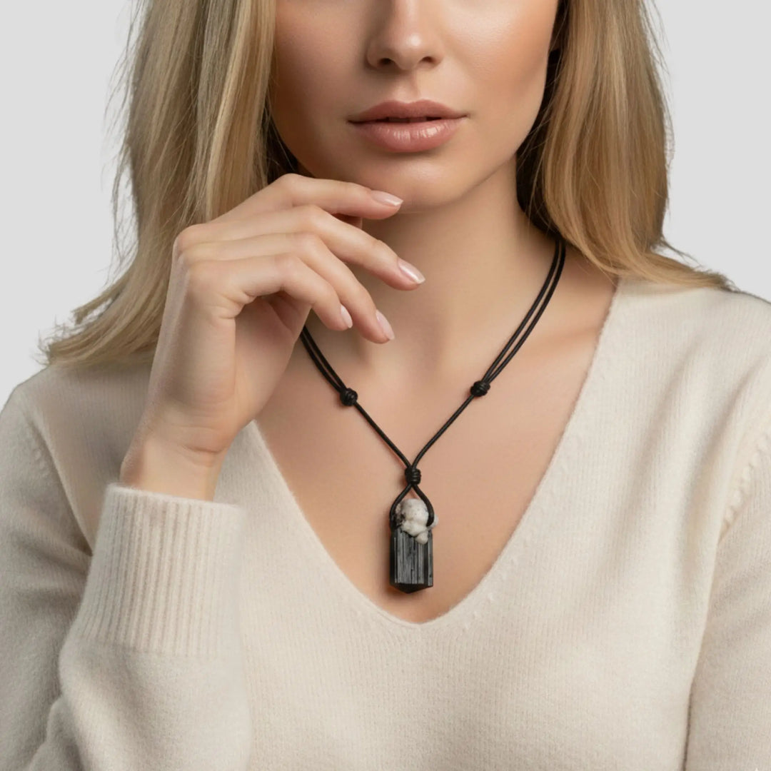 Woman wearing a necklace with a raw black tourmaline pendant against a neutral background
