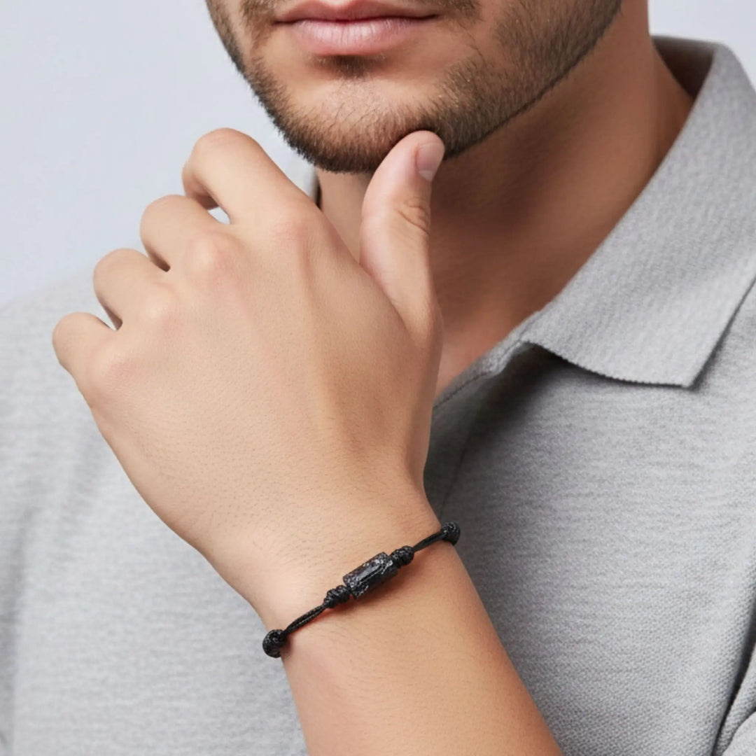 Man wearing a raw black tourmaline bracelet on his wrist with a neutral background