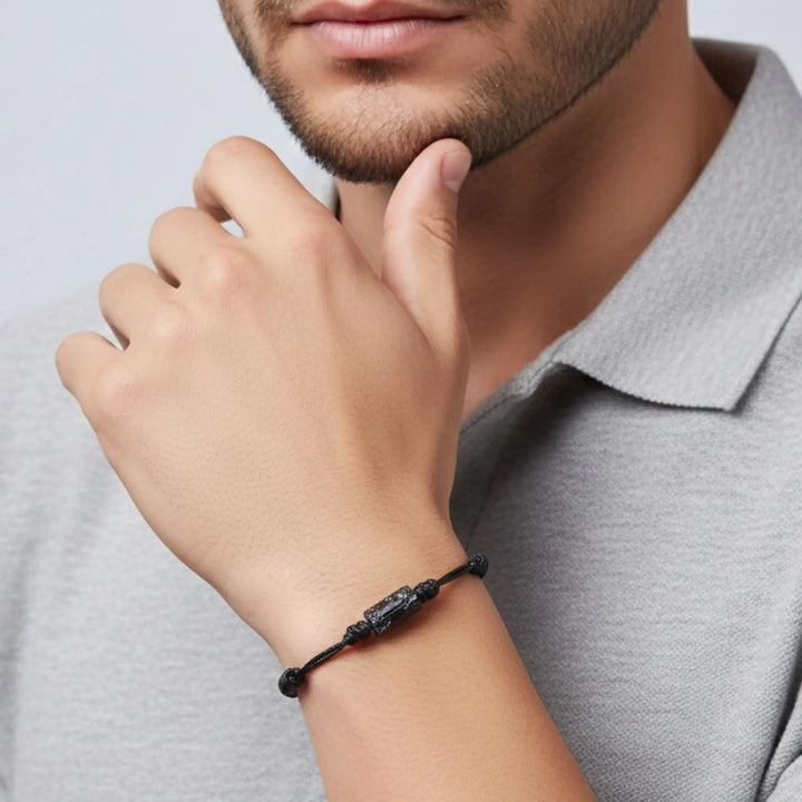 Man wearing a raw black tourmaline bracelet on his wrist with a neutral background