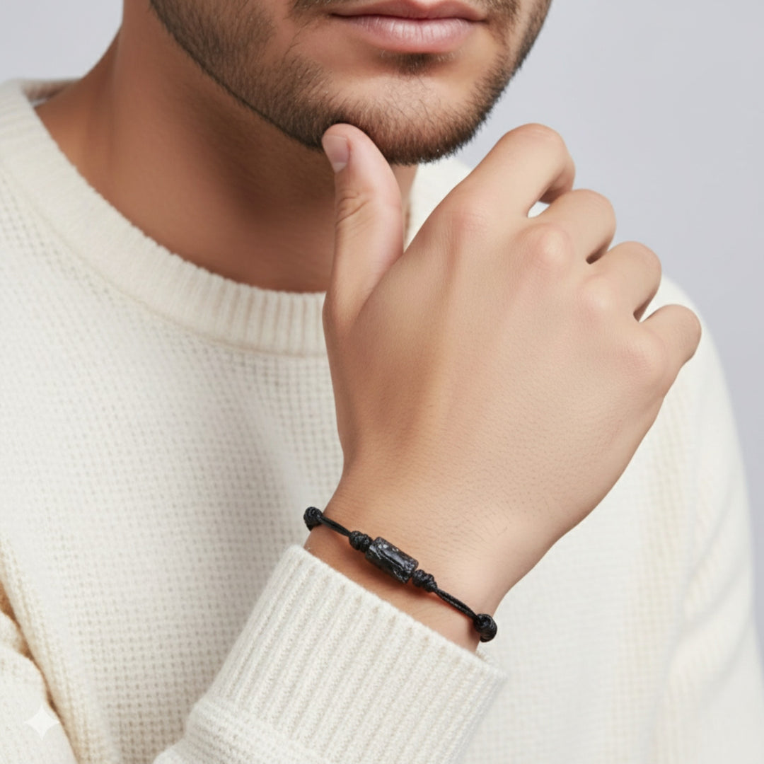 Man wearing raw black tourmaline single bead bracelet on red waxed nylon cord.
