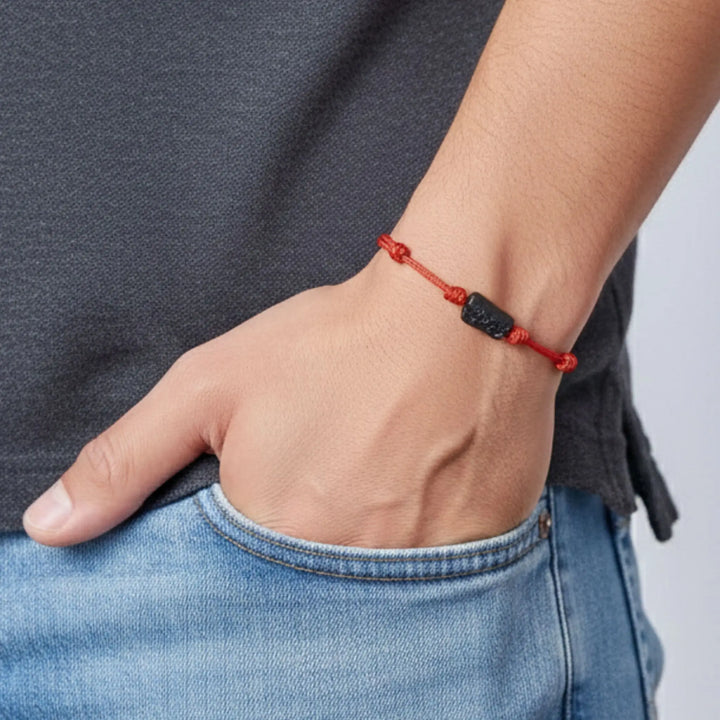 Man wearing raw black tourmaline single bead bracelet on red waxed nylon cord.
