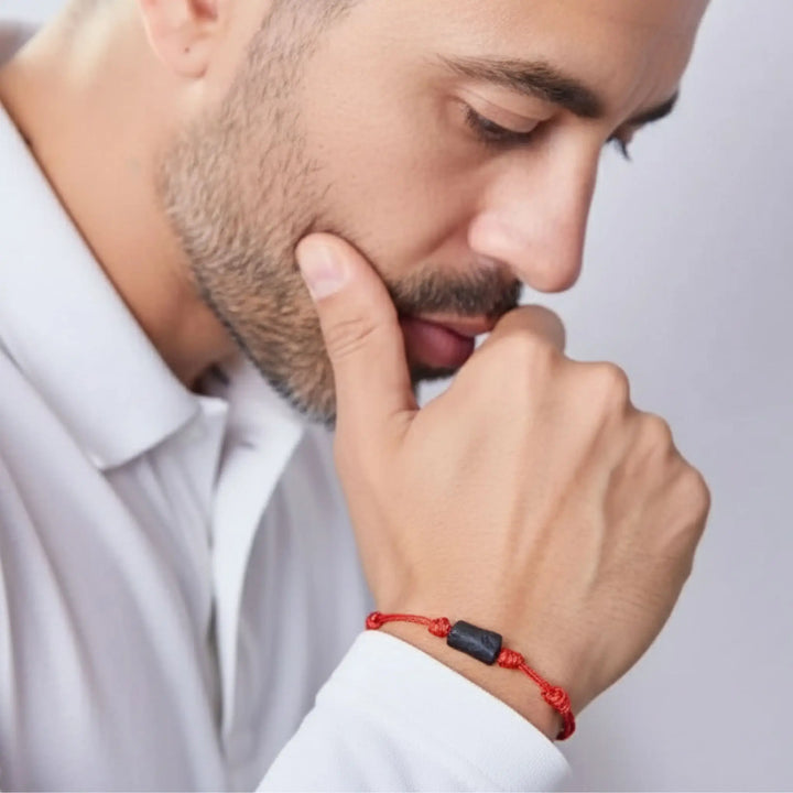 Man wearing raw black tourmaline single bead bracelet on red waxed nylon cord.
