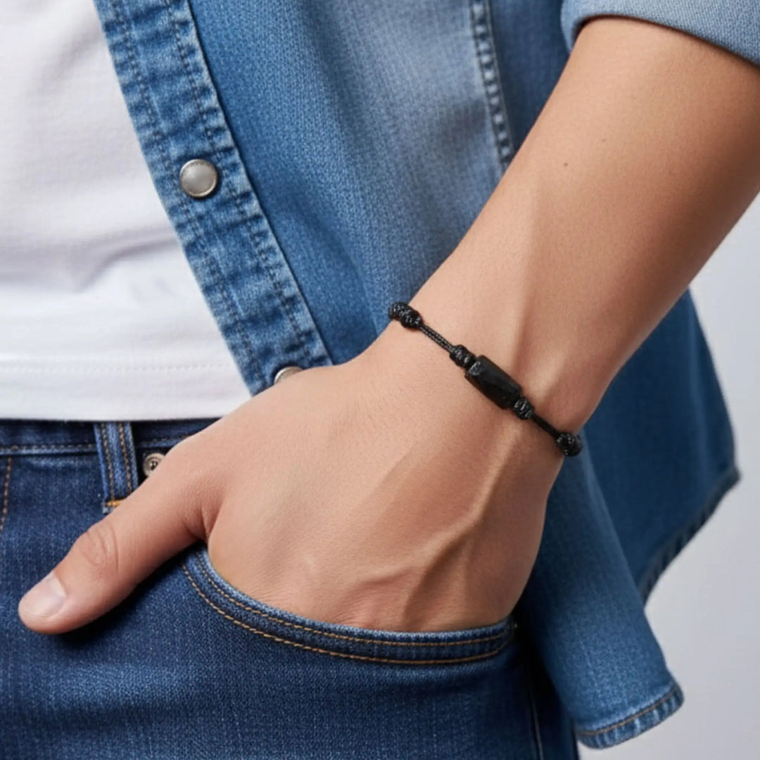 Man wearing raw black tourmaline single bead bracelet on black waxed nylon cord.
