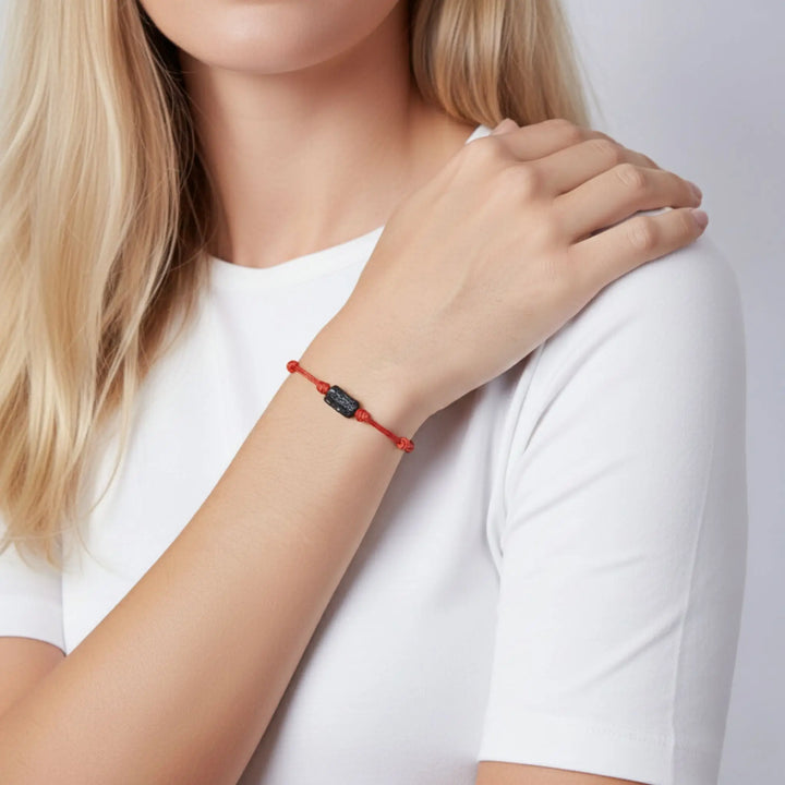 Woman wearing raw black tourmaline single bead bracelet on red waxed nylon cord.
