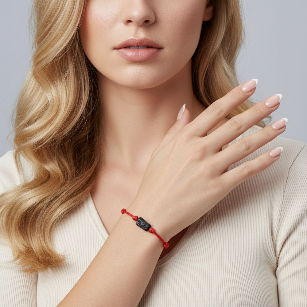 Woman wearing raw black tourmaline single bead bracelet on red waxed nylon cord.
