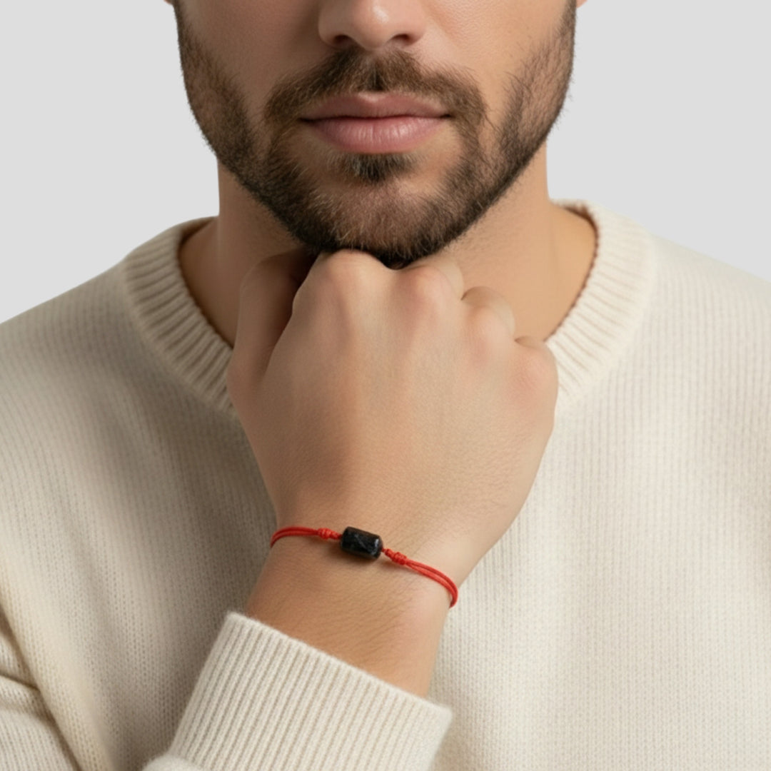 Man wearing raw black tourmaline tube bead bracelet on red nylon cord.
