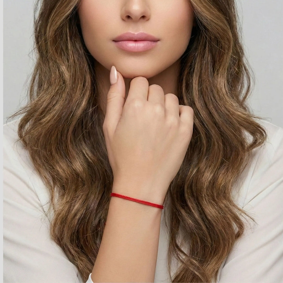 Woman wearing a red bracelet on a plain background