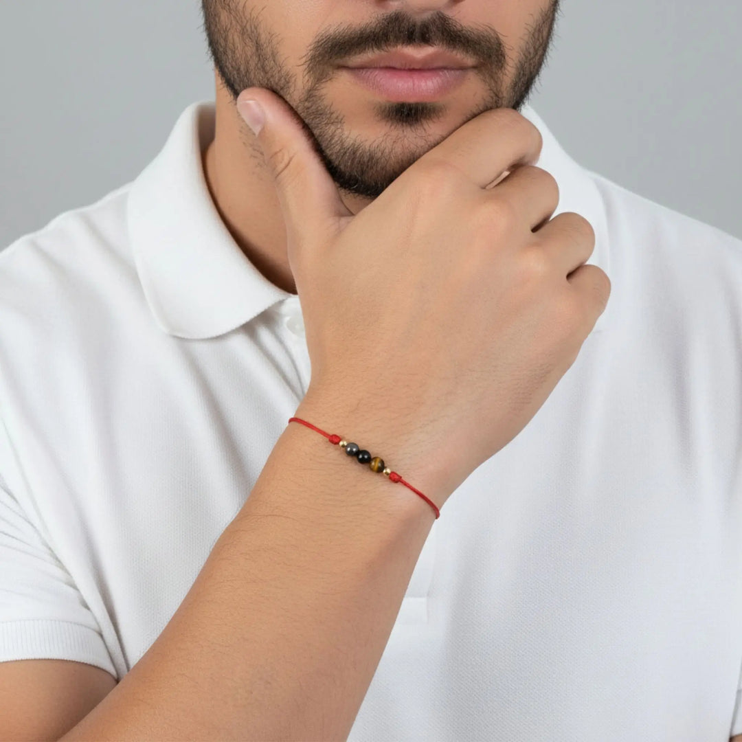 Man wearing a white polo shirt with a red beaded bracelet on his wrist.