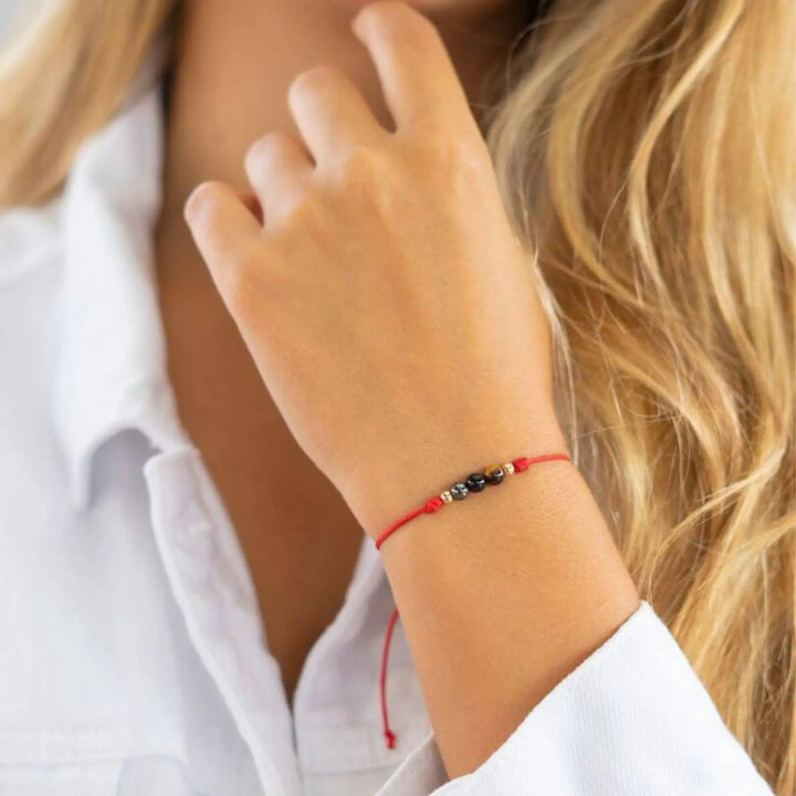 Close-up of a person wearing a red bracelet with small beads.