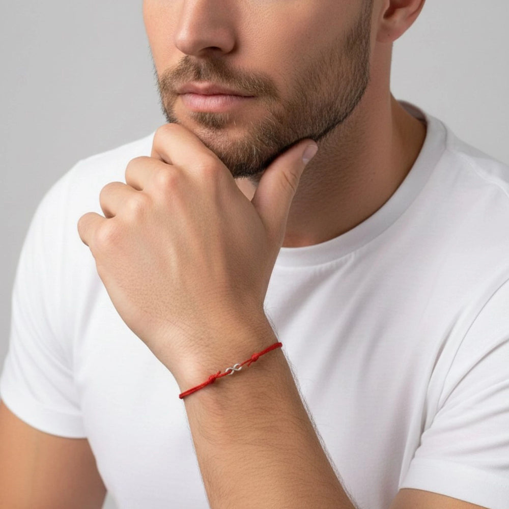 Man wearing a red bracelet on his wrist with a neutral background