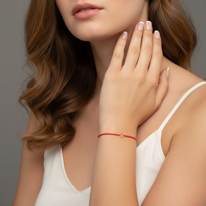 Woman wearing a red bracelet on a neutral background