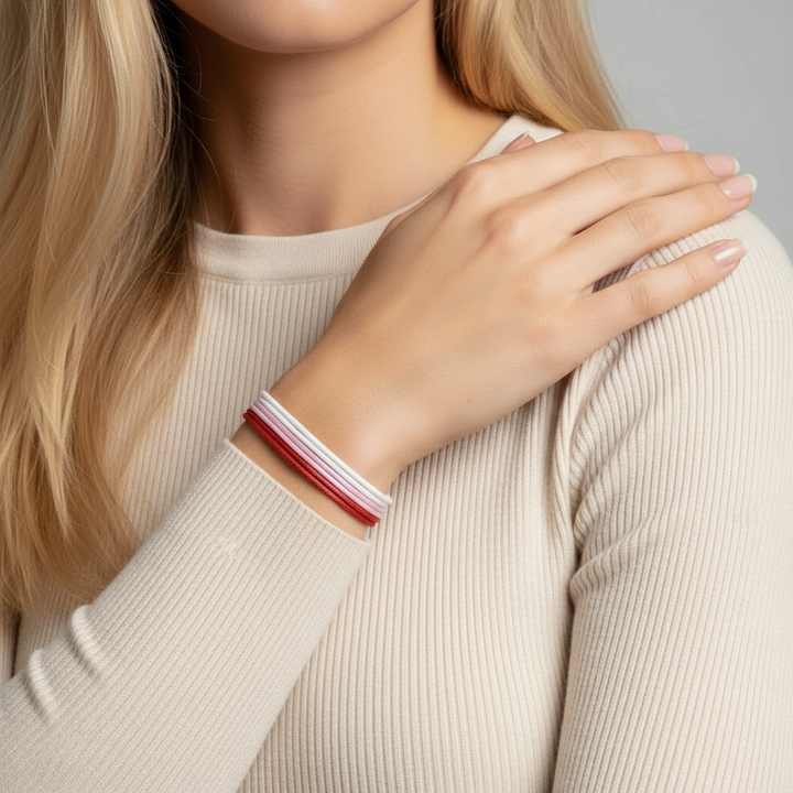Woman wearing a beige sweater with a red and white bracelet on her wrist.