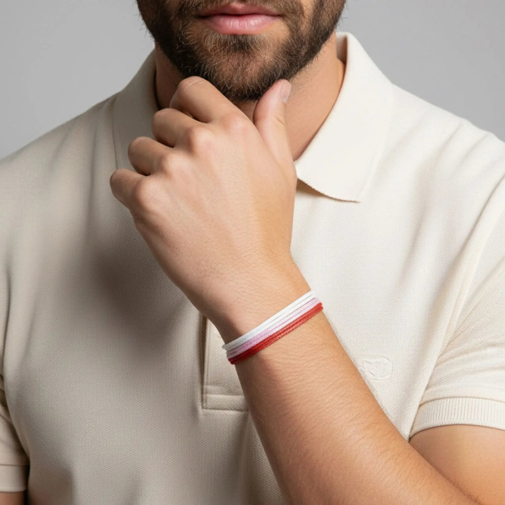 Person wearing a red and white bracelet on a plain background