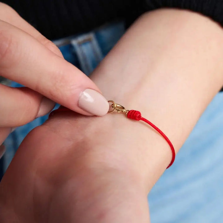 Woman wearing a classic red string bracelet with a 14K solid gold clasp on their wrist - Luck Strings