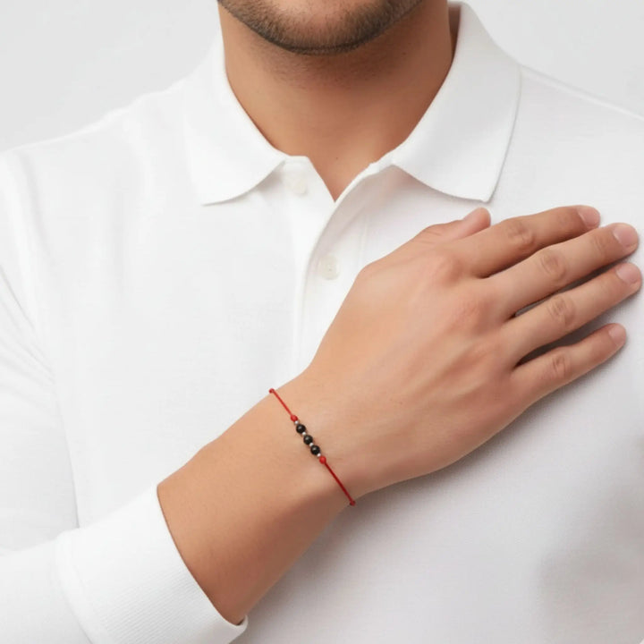 Close-up of a men with a red string black tourmaline beaded bracelet on her wrist.