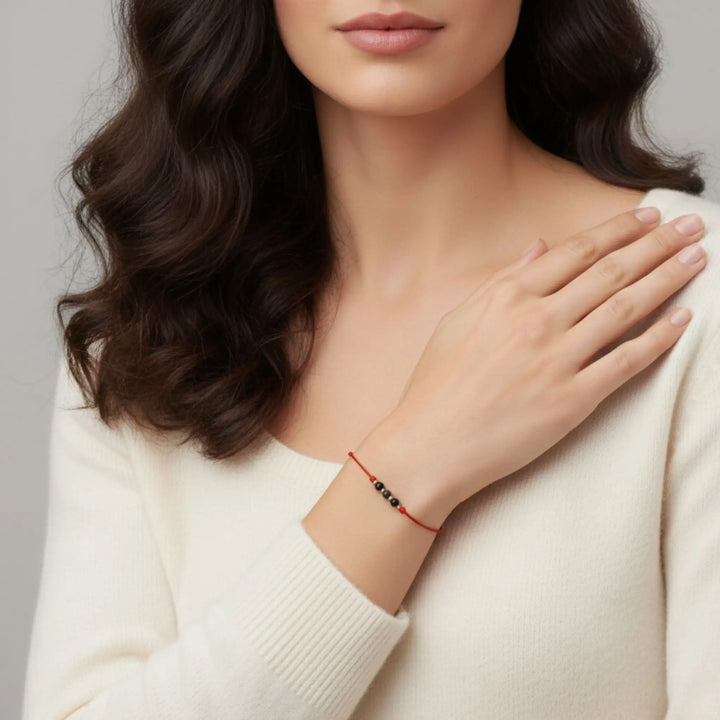 Close-up of a woman with long  hair and a red string black tourmaline bracelet on her wrist.