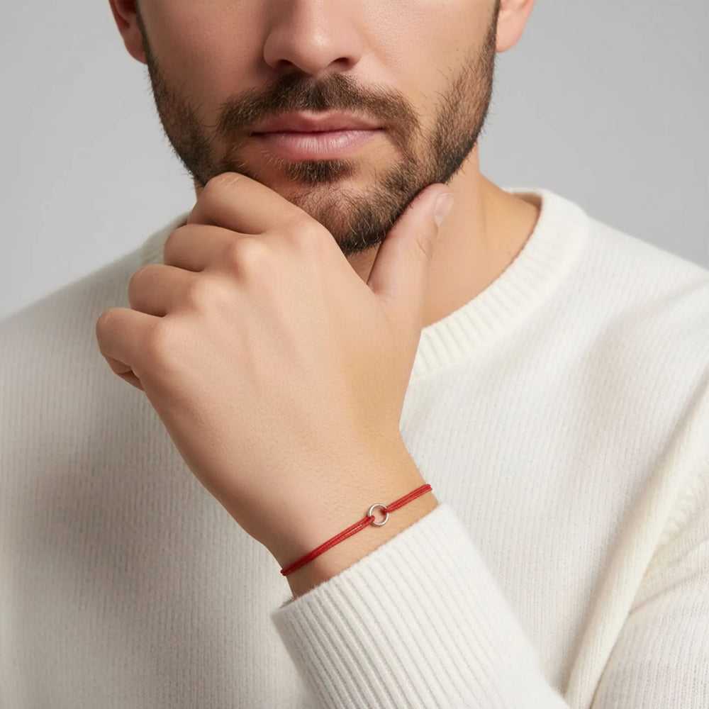 Man wearing a red bracelet on a neutral background
