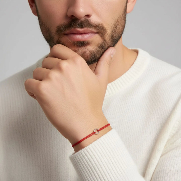 Man wearing a red bracelet on a neutral background