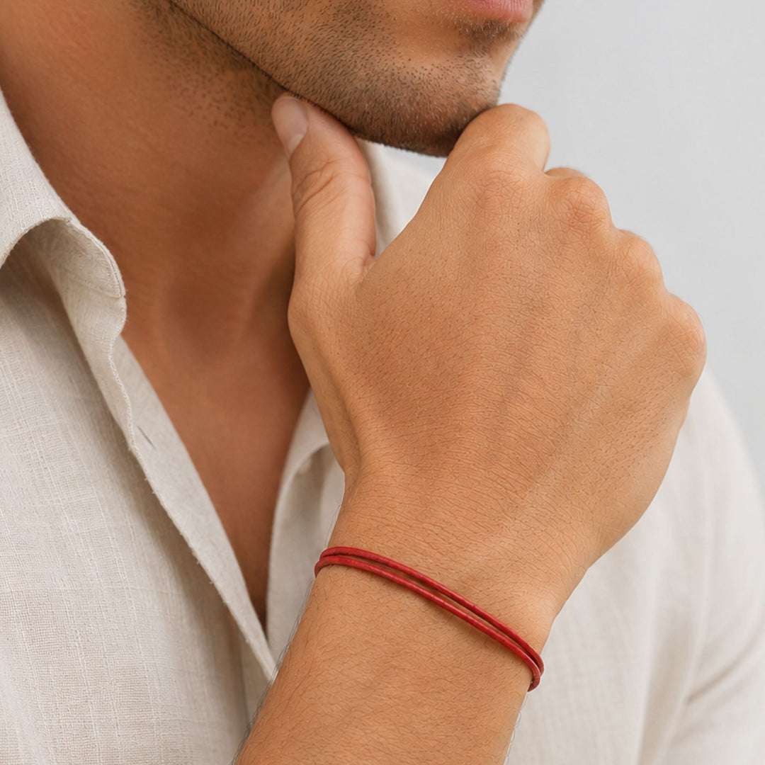 Person wearing a red bracelet on a neutral background