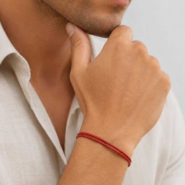 Person wearing a red bracelet on a neutral background