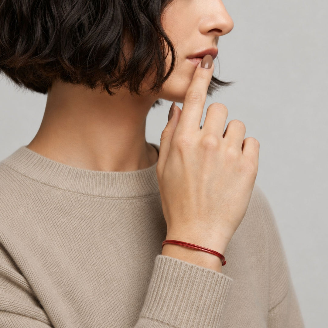 Person wearing a beige sweater with a red bracelet 