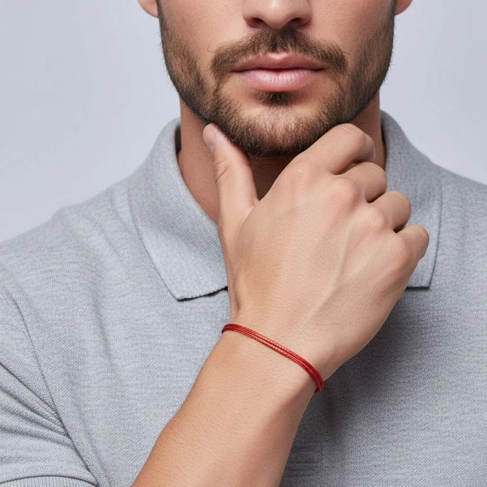 Man wearing a gray polo shirt with a red bracelet on his wrist, against a light gray background