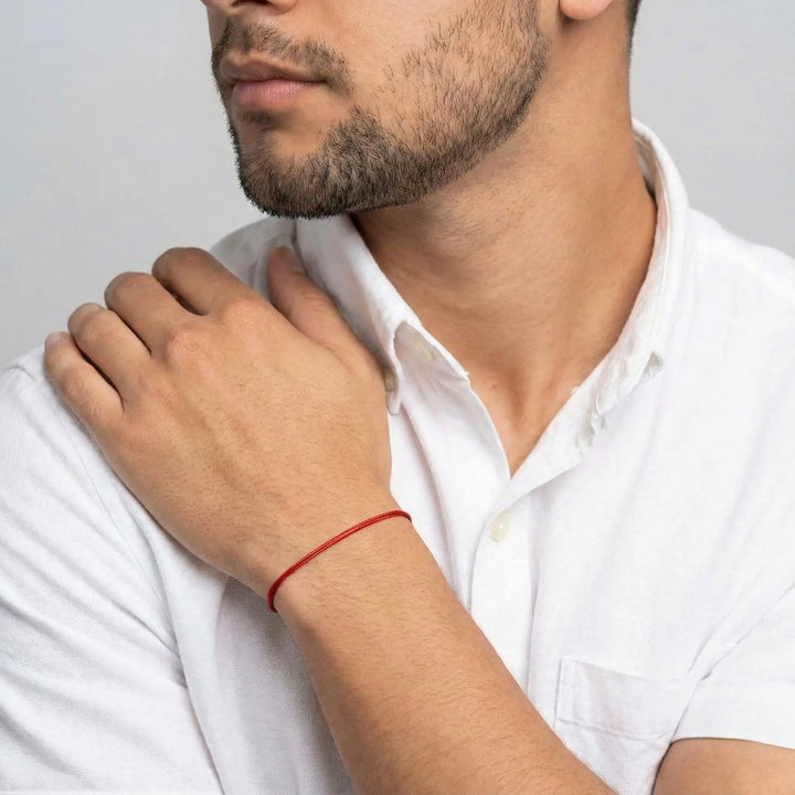 Man wearing a white shirt with a red bracelet on his wrist.