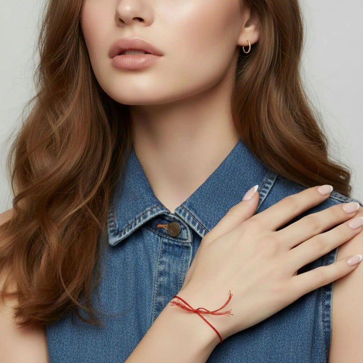 Woman wearing a red bracelet on her wrist, with a neutral background