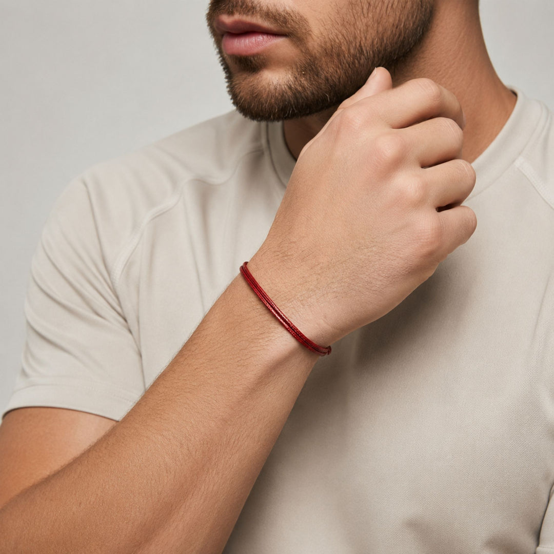 Man wearing a red bracelet on a plain background