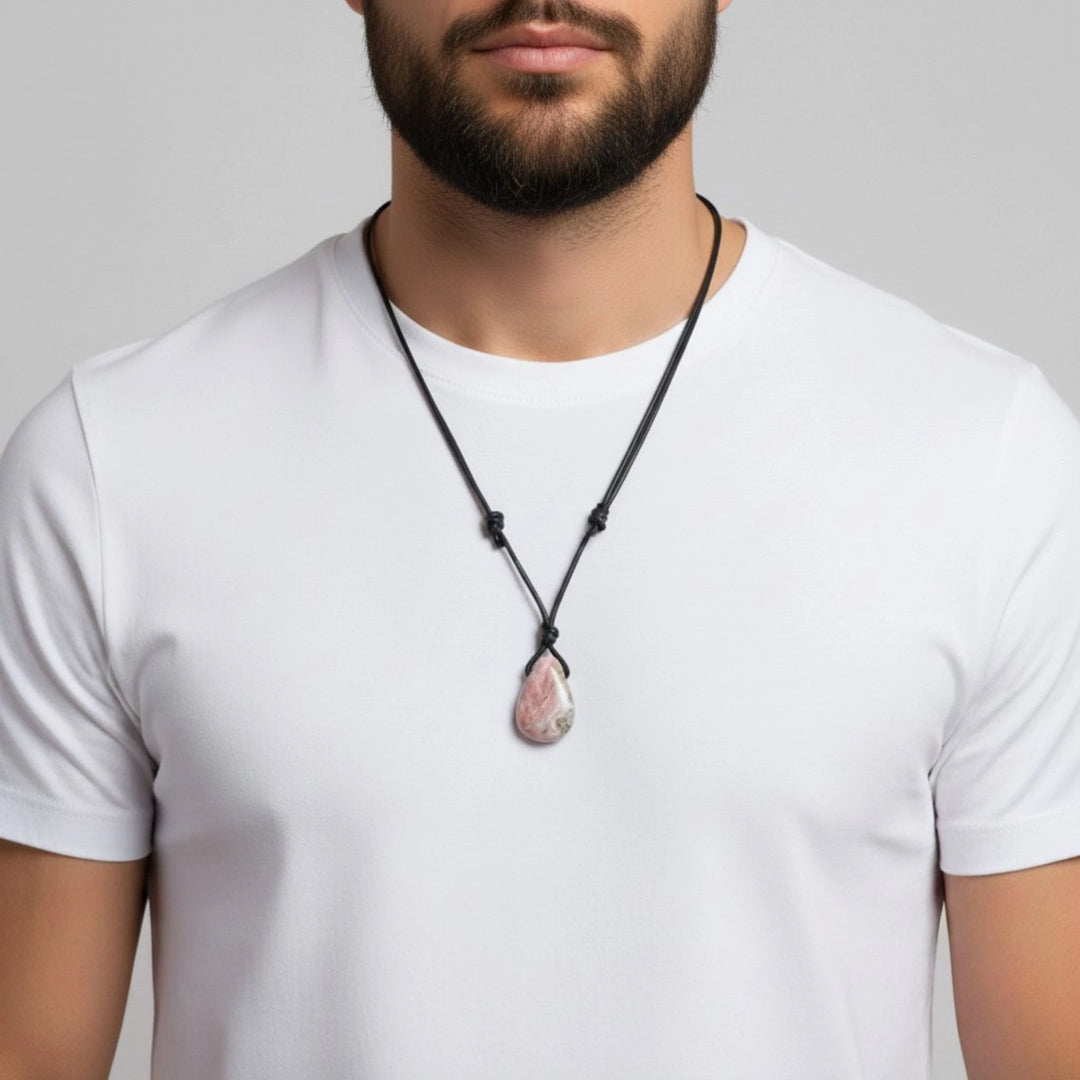 Man wearing a white t-shirt with a black necklace featuring a pink rhodochrosite pendant against a gray background