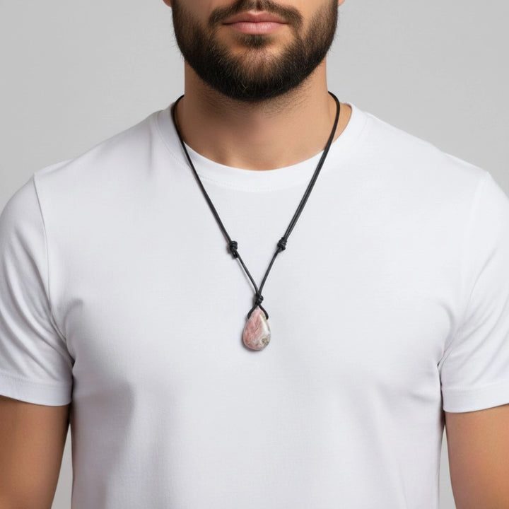 Man wearing a white t-shirt with a black necklace featuring a pink rhodochrosite pendant against a gray background