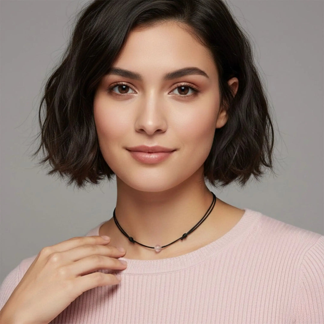Woman wearing a rose quartz necklace against a gray background