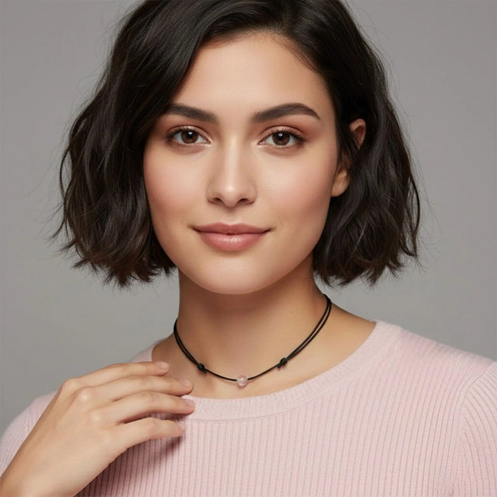 Woman wearing a rose quartz necklace against a gray background