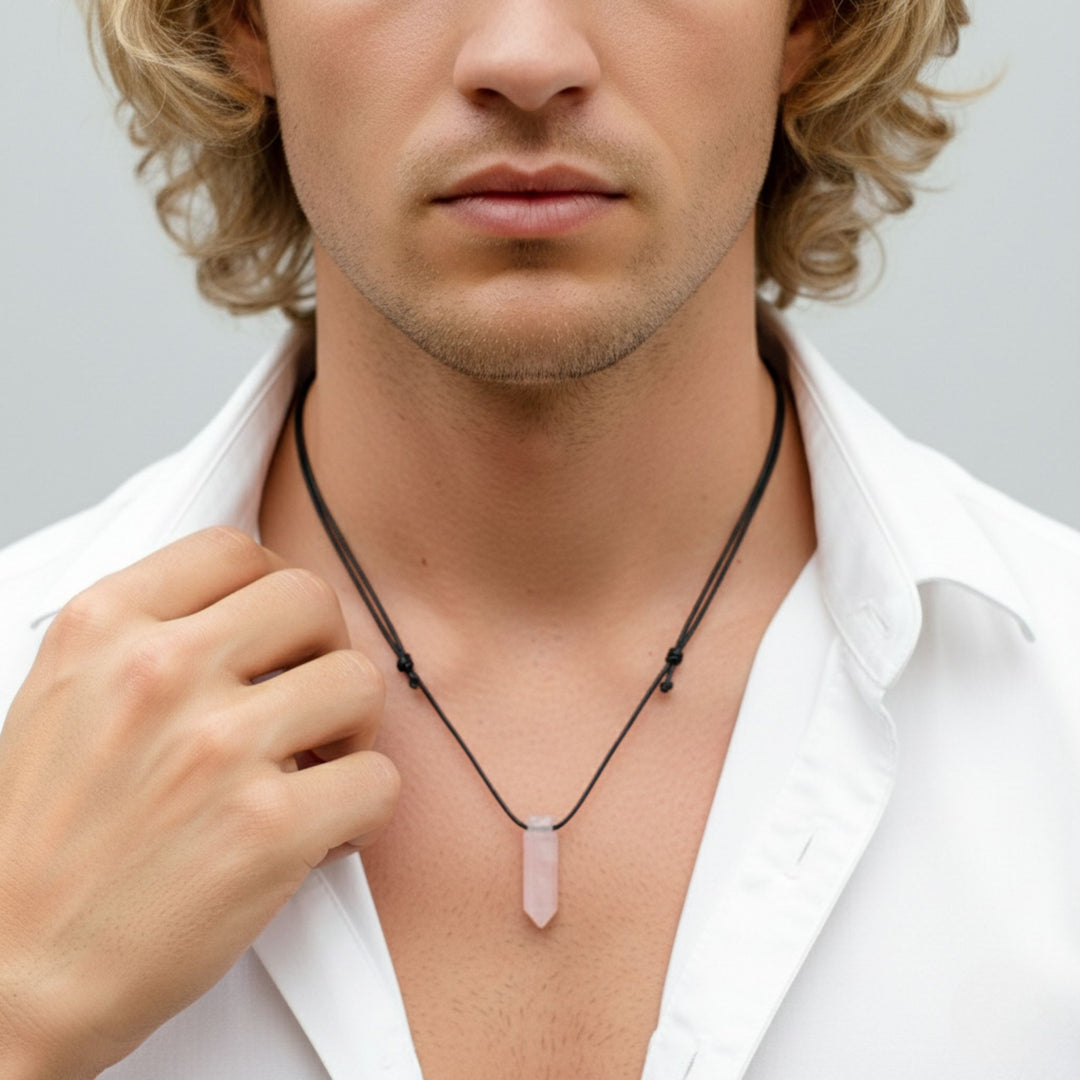 Man wearing a white shirt with a necklace featuring a pink pendant against a light gray background