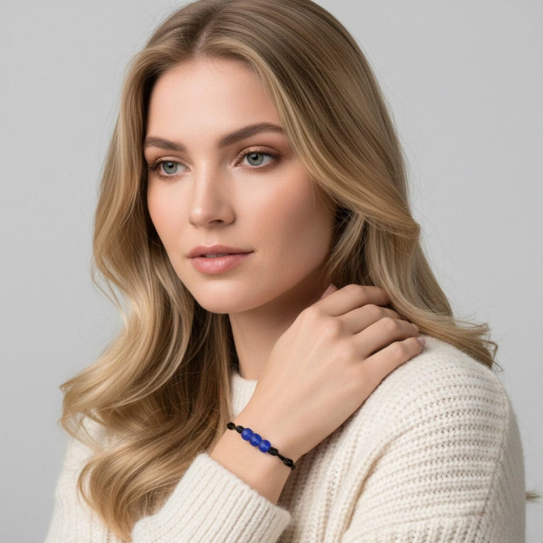 Woman wearing a white sweater and blue beaded bracelet on a gray background