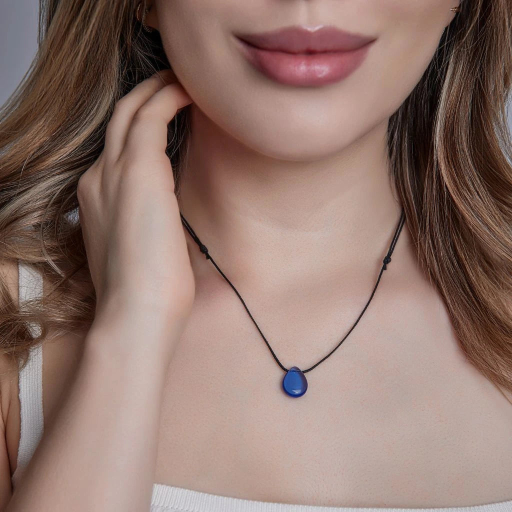 A person wearing a white choker necklace with a blue teardrop-shaped pendant on a wax cotton cord.