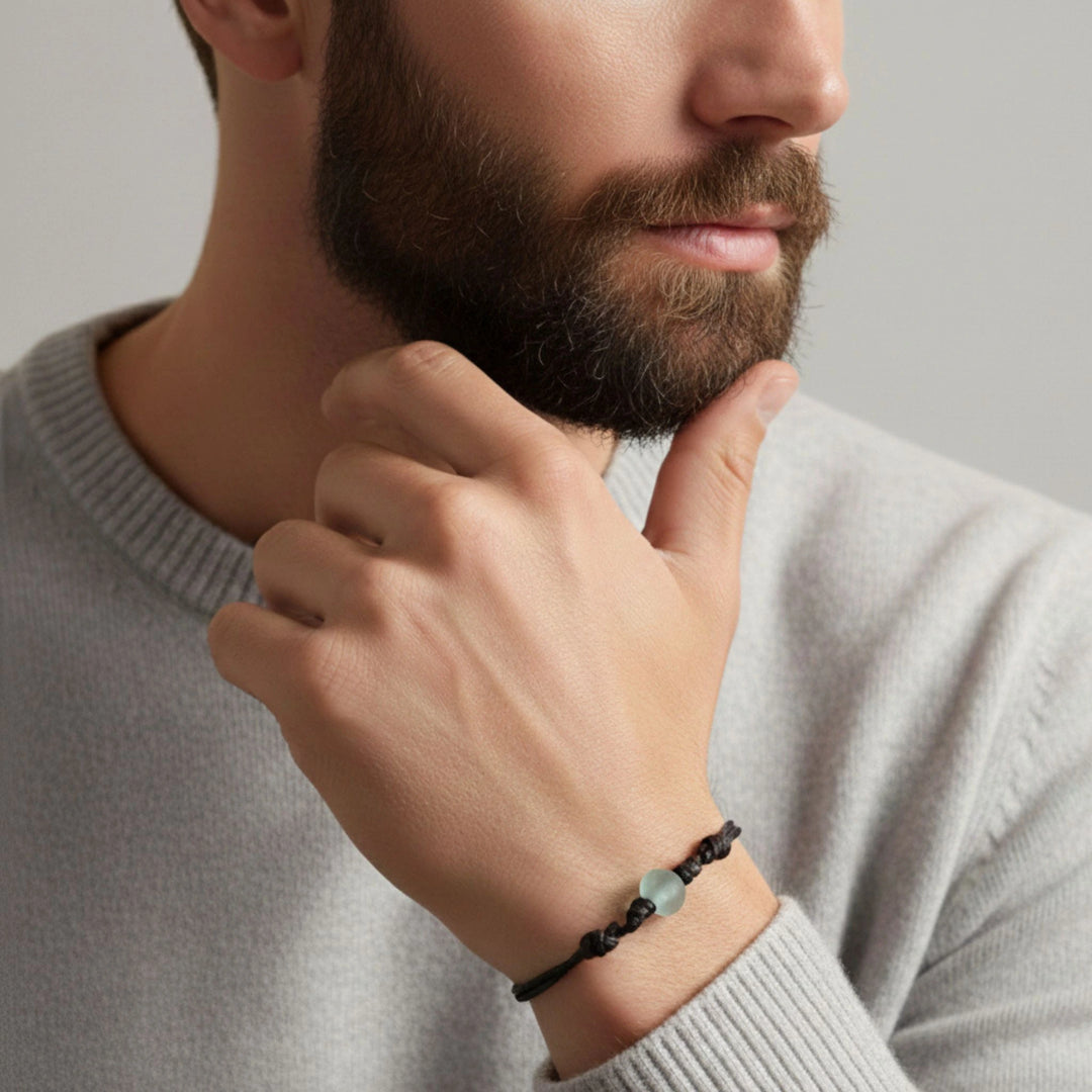 Man wearing a glass bracelet on his wrist with a neutral background