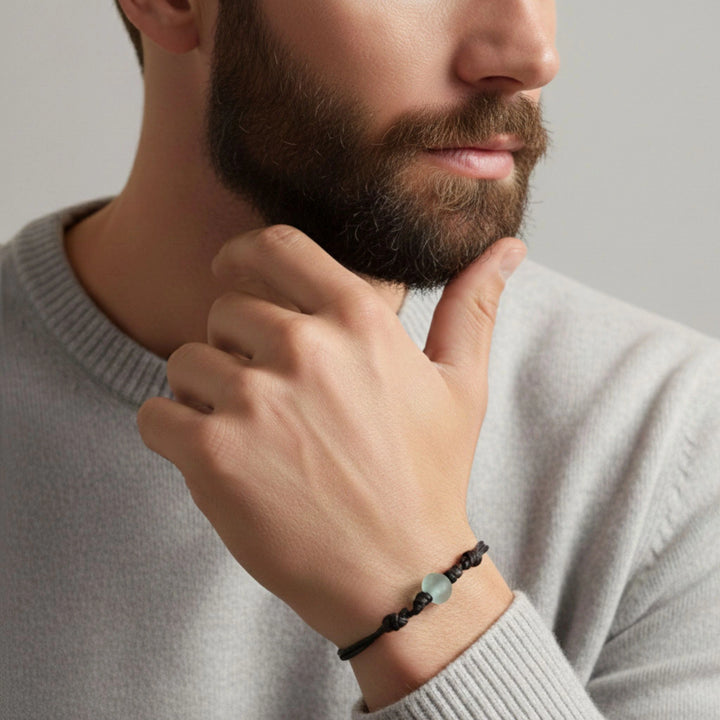 Man wearing a glass bracelet on his wrist with a neutral background