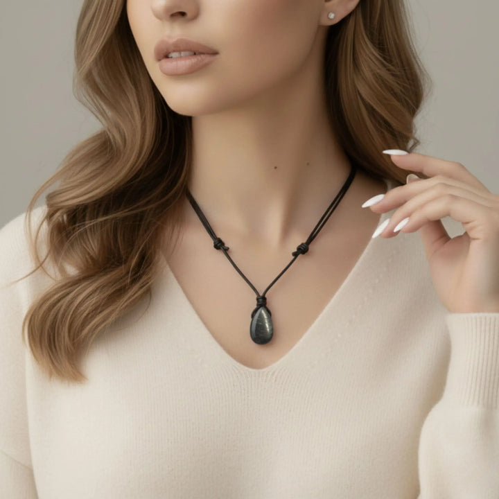 Woman wearing a black shungite necklace with a beige background
