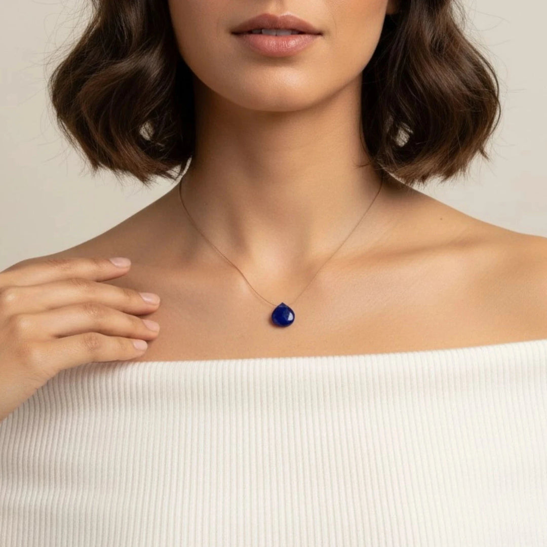 Woman wearing a necklace with a lapis lazuli pendant against a neutral background